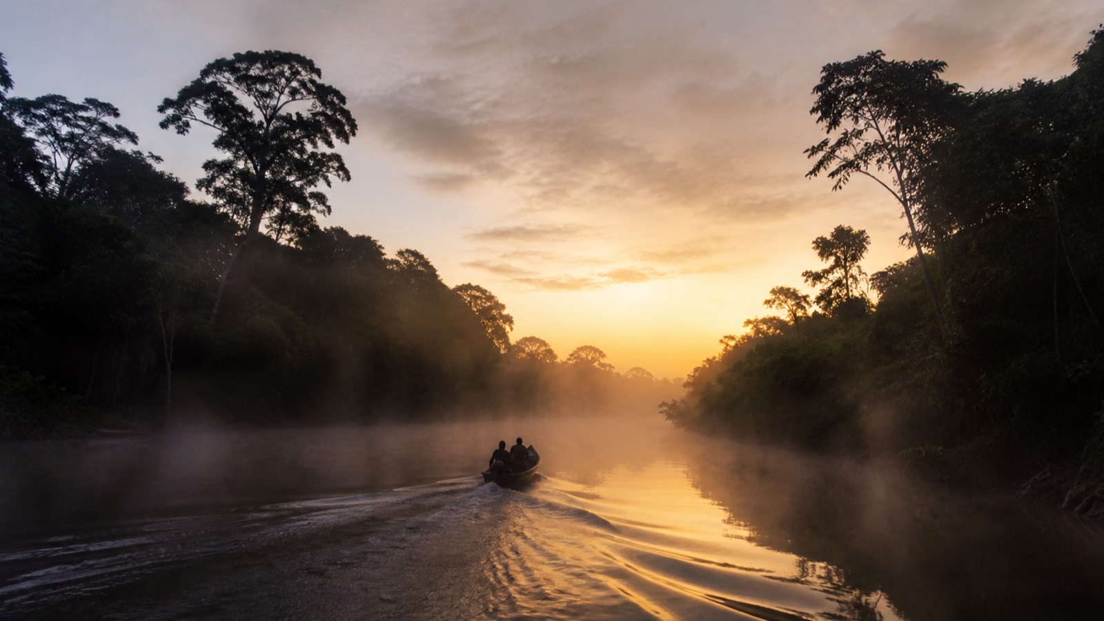 Wooden boat resting on still river water at dawn
